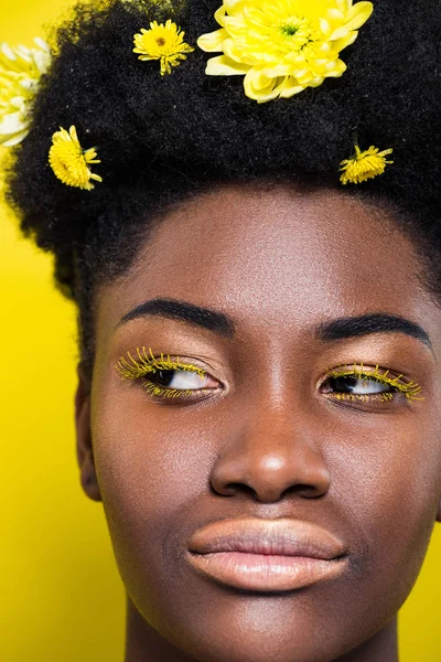 Portrait of african american woman with flowers in hair on yellow — Stock Photo