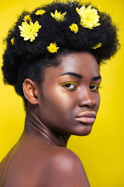 Hermosa mujer afroamericana con crisantemos en pelo aislado en amarillo - foto de stock