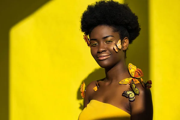 Sorridente bella donna africana americana con farfalle sul giallo — Foto stock