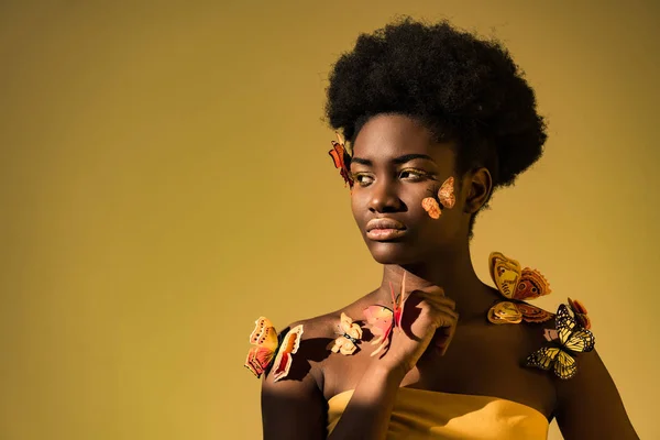 Dreamy african american woman with butterflies looking away on brown — Stock Photo