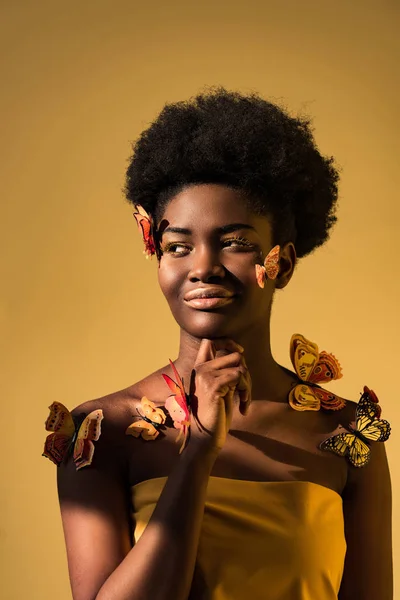 Femme africaine américaine rêveuse avec des papillons regardant loin sur brun — Photo de stock