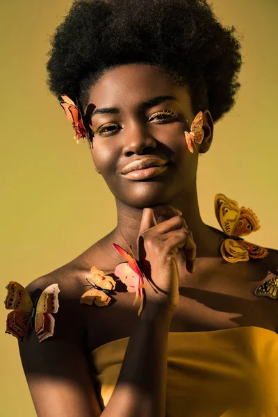 Радостный африканский американец с бабочками, смотрящими на камеру, изолированную от коричневого — стоковое фото