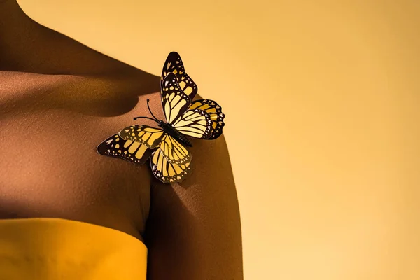Обітнуте подання афроамериканської жінки з метеликом на плечі помаранчевого — стокове фото