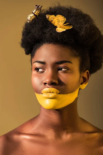 Hermosa mujer afroamericana con mariposas y el arte del cuerpo amarillo en marrón - foto de stock