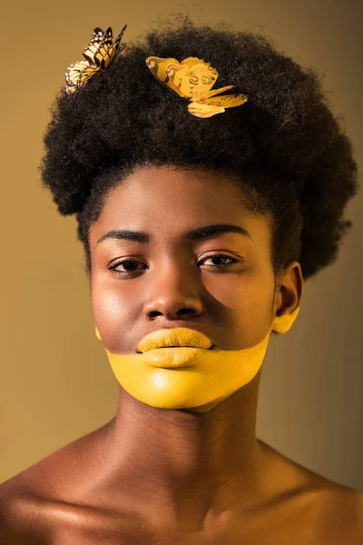 Hermosa mujer afroamericana con mariposas y el arte del cuerpo amarillo en marrón - foto de stock
