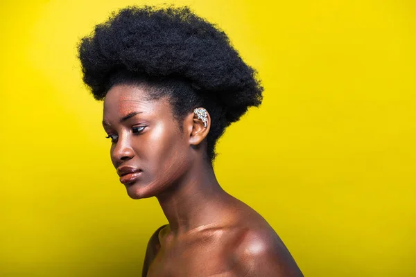 Pensivo attraente donna africana americana con polsino orecchio su giallo — Foto stock