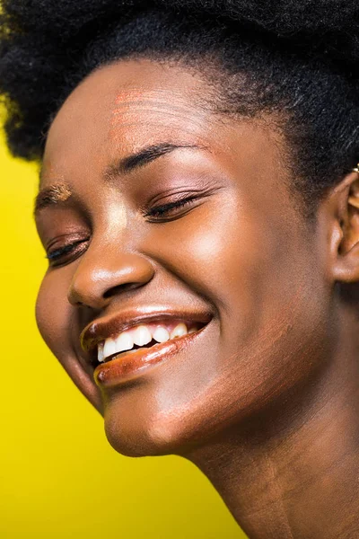 Happy laughing african american woman with closed eyes isolated on yellow — Stock Photo