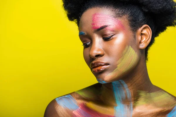 Mujer afroamericana pensativa con arte corporal mirando hacia otro lado en amarillo - foto de stock