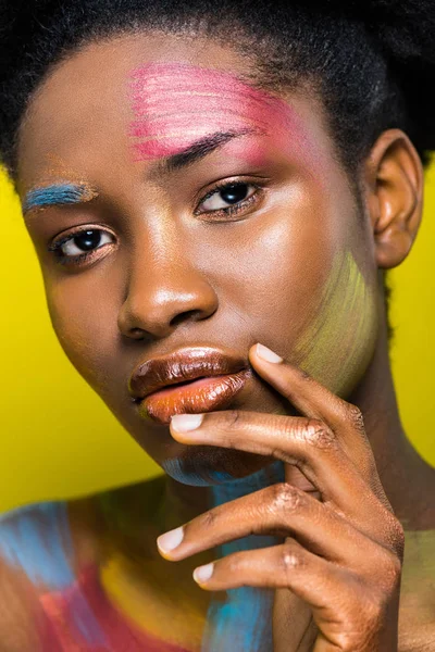 Pensativo afroamericano chica con cuerpo arte tocando los labios aislados en amarillo - foto de stock