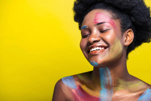 Laughing african american woman with bright body art on yellow — Stock Photo