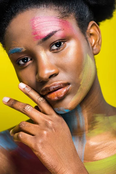 Charming african american woman with colorful body art isolated on yellow — Stock Photo