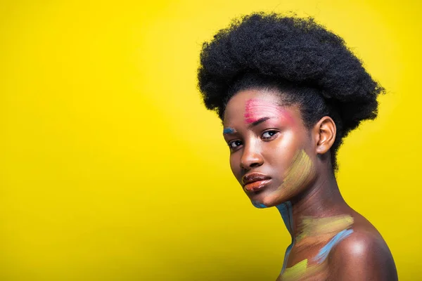 Pensiva donna afroamericana con body art colorato sul giallo — Foto stock