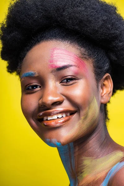 Femme afro-américaine joyeuse avec art corporel souriant à la caméra isolée sur jaune — Photo de stock