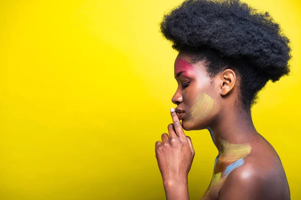 Vista laterale della ragazza afro-americana con body art su giallo — Foto stock