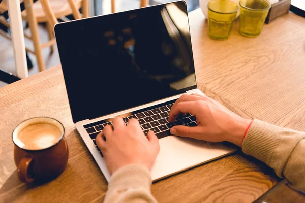 Cropped view of blogger using laptop with blank screen near cup of coffee — Stock Photo