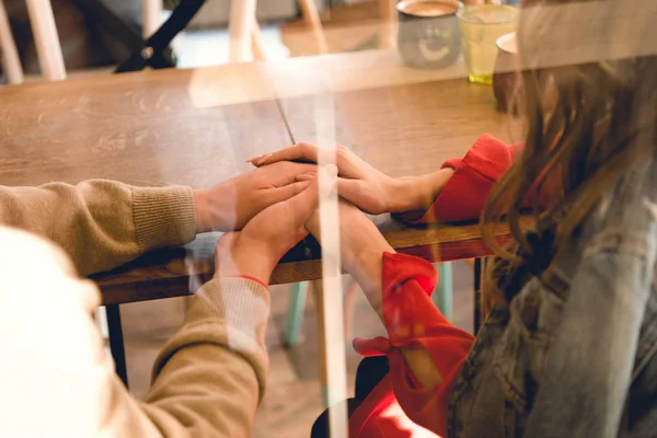 Обрезанный вид пары, держащейся за руки в кафе — стоковое фото