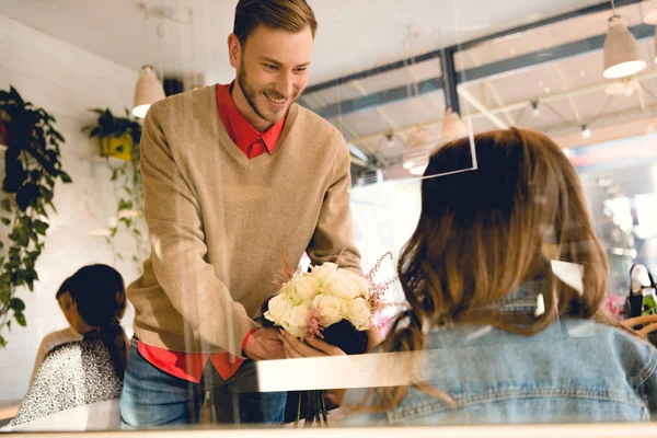 Bello fidanzato dando fiori a donna in caffè — Foto stock