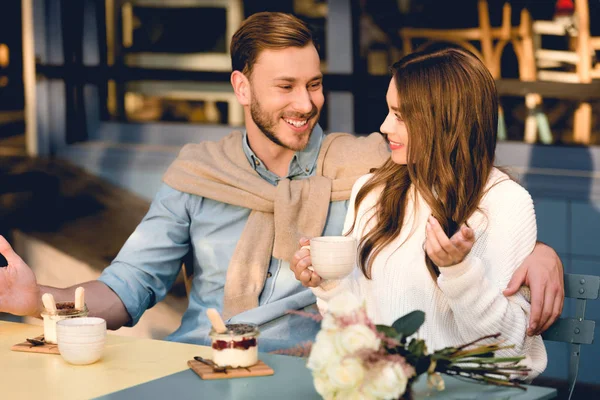 Homme joyeux regardant petite amie heureuse tenant tasse de café — Photo de stock