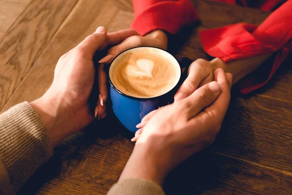 Обрезанный вид мужчины и женщины, держащих чашку кофе — стоковое фото