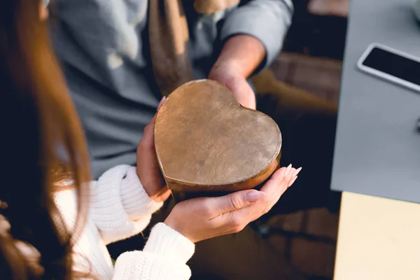 Recortado vista de novio dando corazón-forma caja a la novia - foto de stock