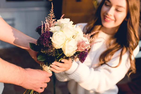 Обрізаний вид чоловіка, що дарує квіти щасливій молодій жінці — стокове фото