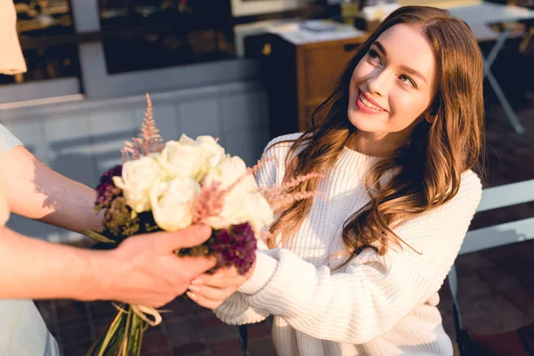 Abgeschnittene Ansicht eines Mannes, der einer fröhlichen jungen Frau Blumen schenkt — Stockfoto