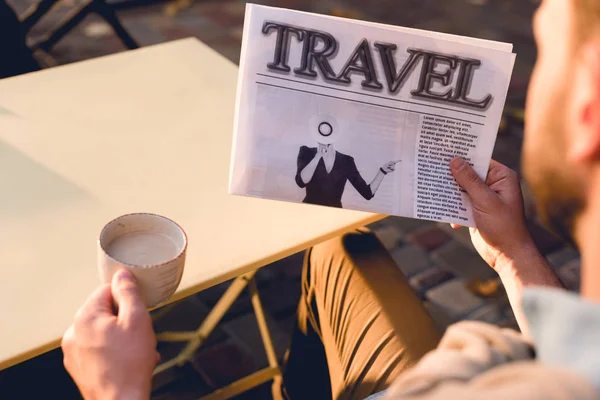 Cropped view of man holding travel newspaper and cup of coffee — Stock Photo