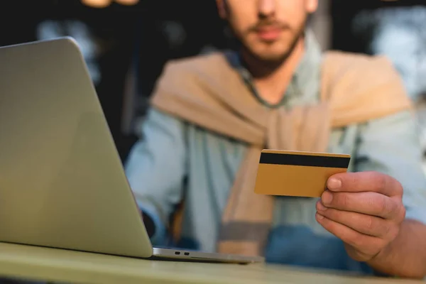 Vue recadrée de l'homme tenant la carte de crédit tout en utilisant un ordinateur portable — Photo de stock