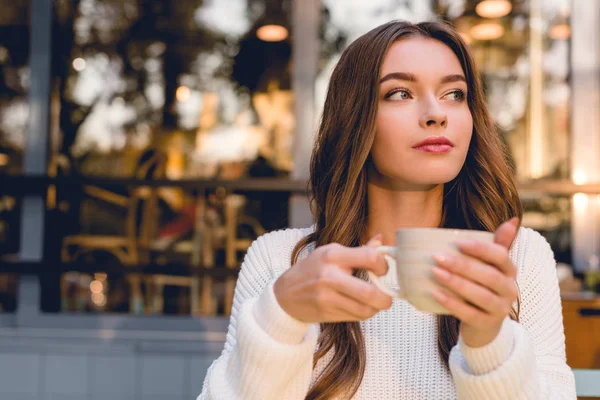 Bela jovem segurando xícara com café no café — Fotografia de Stock