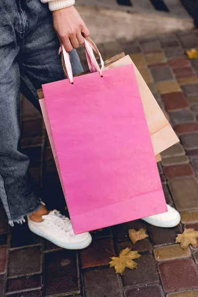 Vista recortada de la mujer joven sosteniendo bolsas de compras de color rosa - foto de stock