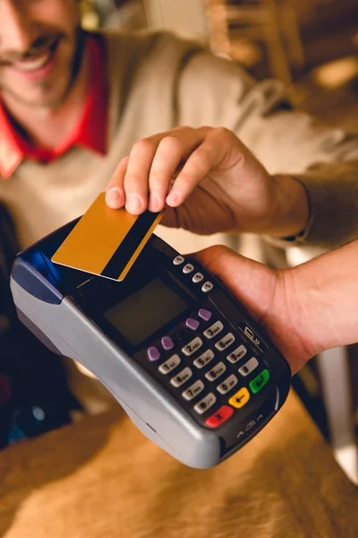 Vista recortada de hombre alegre con tarjeta de crédito mientras paga en la cafetería — Stock Photo