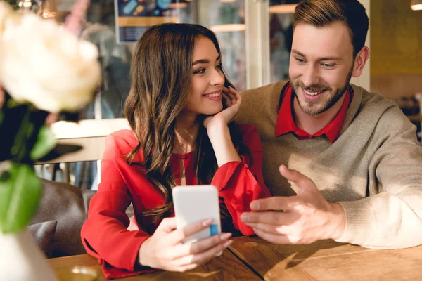 Allegra giovane donna che guarda l'uomo gesticolare mentre guarda smartphone — Foto stock