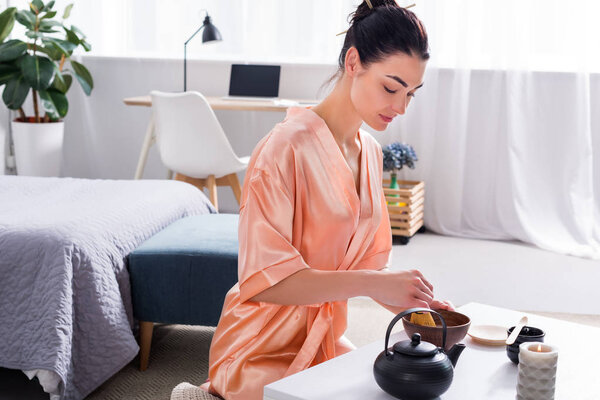 attractive woman in silk bathrobe making tea with whisk while having tea ceremony in morning at home