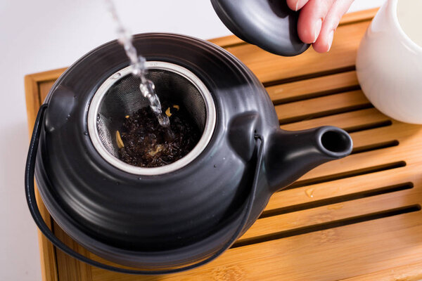 cropped shot of woman making tea while having tea ceremony in morning at home
