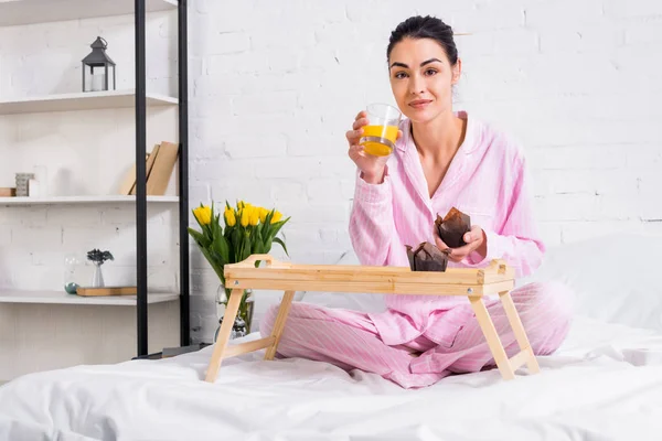 Kvinna Pyjamas Med Glas Apelsinjuice Och Choklad Muffins Sängen Morgon — Gratis stockfoto