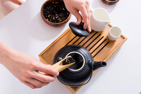 cropped shot of woman making tea while having tea ceremony in morning at home