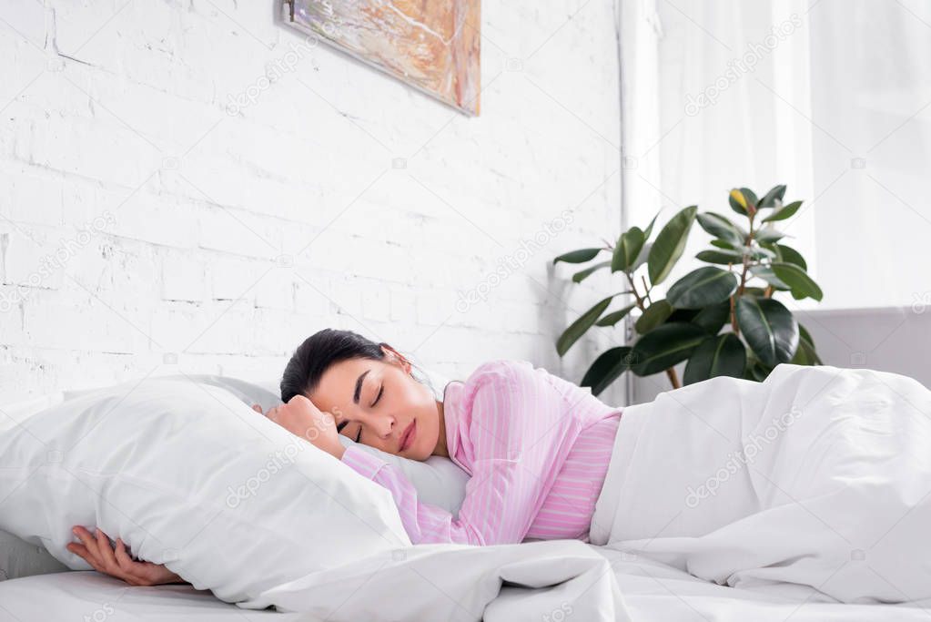 portrait of woman in pink pajamas sleeping in bed at home
