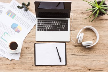 düz lay boş ekran, boş defter, kulaklık ve ahşap masa üstü kağıtlara ile dizüstü bilgisayar ile