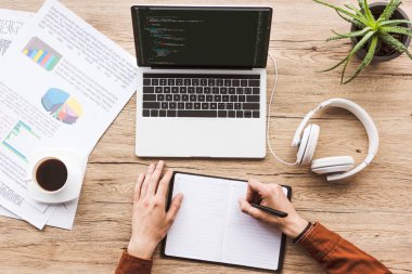 kısmi notlar notebook dizüstü, kağıtları, fincan kahve ve kulaklık ile işyerinde yapma adam görünümünü