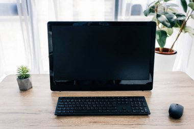 ahşap masa üzerinde boş bilgisayar monitörü, Saksı bitki ve bilgisayar fare ve klavye önden görünüm 