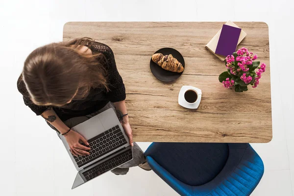 Översiktsbild Kvinna Att Skriva Laptop Och Sitter Bord Med Croissant — Gratis stockfoto