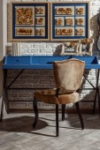 Interieur eines modernen Wohnzimmers im Retro-Stil mit blauem Tisch, Stuhl und Fotos in Rahmen