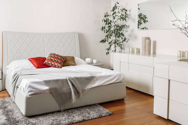 интерьер современной светлой спальни с цветными подушками на кровати
