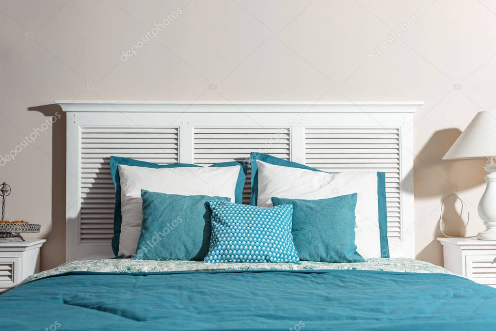 interior of modern bedroom with white wooden bed and blue bedsheets