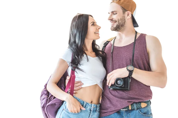 カメラとバックパックを抱いて 白で隔離 お互いを見て笑みを浮かべて観光客のカップル — ストック写真