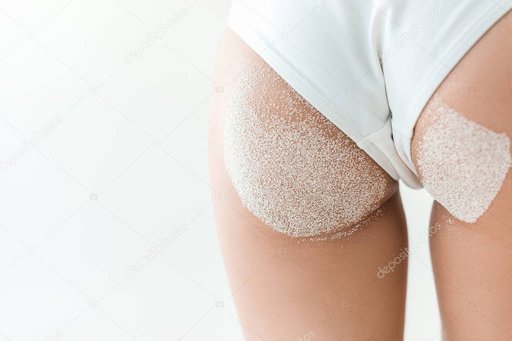 partial view of beautiful buttocks in white bikini with sand, isolated on white