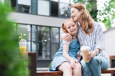 mutlu anne ve kızı sokakta bankta oturan