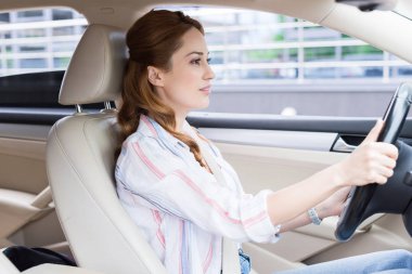 side view of attractive woman driving car alone clipart