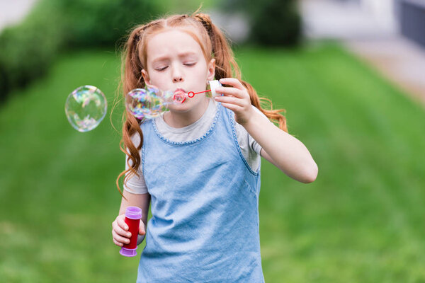 portrait of cute child blowing soap bubbles in park