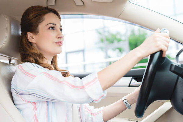 side view of attractive woman driving car alone